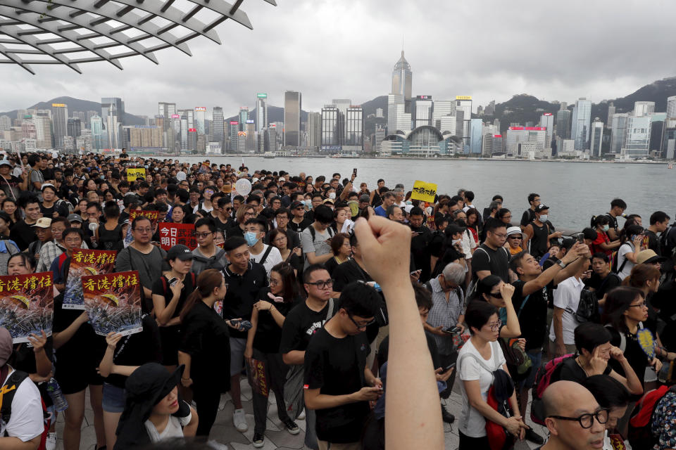 FILE - In this file photo, protesters march near the skyline of Hong Kong, on July 7, 2019. The exodus of tens of thousands of professionals from Hong Kong triggered by Beijing's crackdown on its civil liberties is being offset by new arrivals: mainland Chinese keen to move to the former British colony. (AP Photo/Kin Cheung, File)