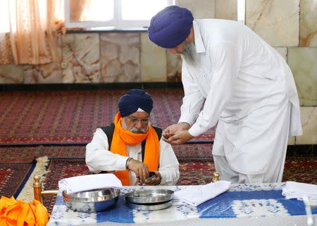 An Afghan Sikh (R) receives karah prasad, a sweet pudding offering given out to a congregation at the end of prayer, inside a Gurudwara, or a Sikh temple, during a religious ceremony in Kabul, Afghanistan June 8, 2016. REUTERS/Mohammad Ismail