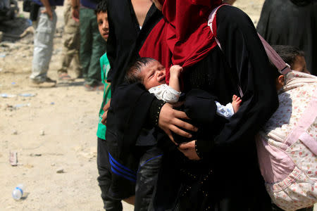 A displaced Iraqi woman who fled from clashes, carries her baby in western Mosul, Iraq, June 3, 2017. REUTERS/Alaa Al-Marjani