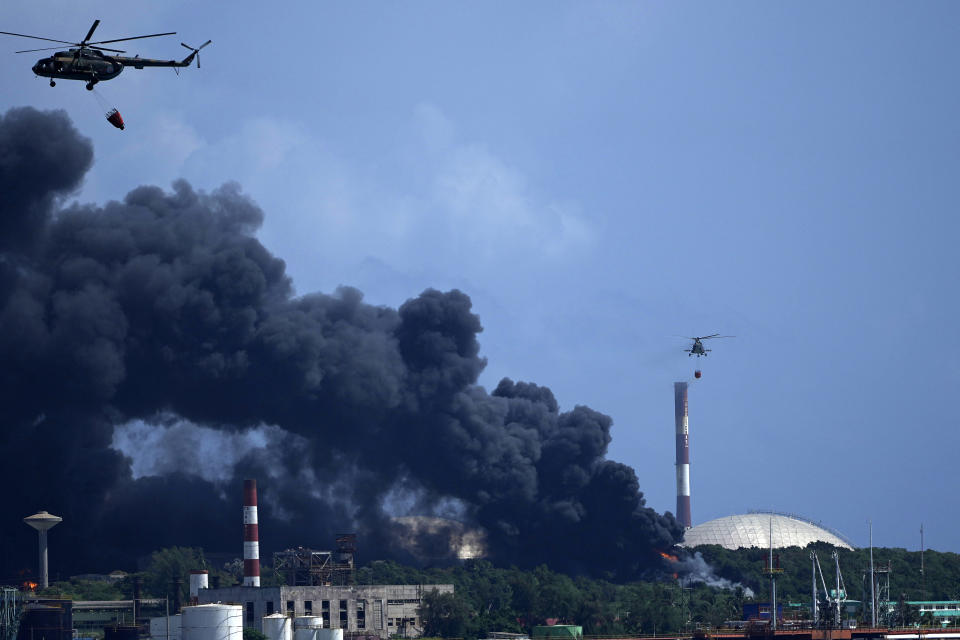 Helicópteros arrojan agua sobre la Base de Supertanqueros de Matanzas, mientras bomberos y especialistas trabajan para extinguir un incendio que fue causado por una tormenta eléctrica la víspera, en Matanzas, Cuba, el sábado, 6 de agosto del 2021. El incendio y cuatro explosiones asociadas dejaron más de 70 heridos. (AP Foto/Ramón Espinosa)