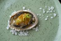 A cooked abalone is displayed in a restaurant in Hermanus, South Africa, April 27, 2023. Today, the abalone industry is a mixture of illegal poaching, farmed varieties and minuscule catches for local farmers. (AP Photo/Jerome Delay)