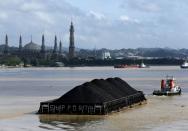 A tug boat pulls a coal barge along the Mahakam River in Samarinda