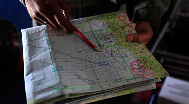 A pilot of a Royal Malaysian Air Force CN-235 aircraft shows a map during a search and rescue operation for the missing Malaysia Airlines plane over the waters at Malacca straits. Photo: AP.