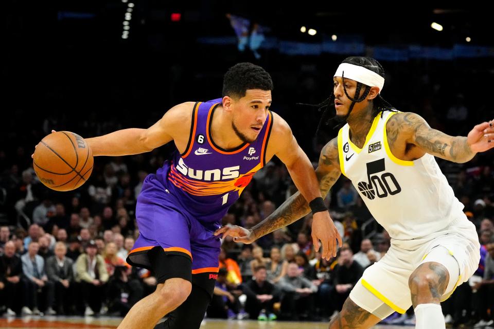 November 26, 2022; Phoenix, Ariz; USA; Suns guard Devin Booker (1) drives against Jazz guard Jordan Clarkson during a game at the Footprint Center. 