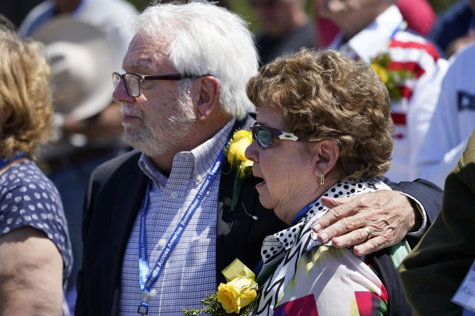 Monica Young is comforted by her husband, Richard Young, while attending the unveiling of a monument to honor the military passengers of Flying Tiger Line Flight 739, Saturday, May 15, 2021, in Columbia Falls, Maine. Monica's father, SFC John Wendall, was among those killed on the secret mission to Vietnam in 1962. (AP Photo/Robert F. Bukaty)