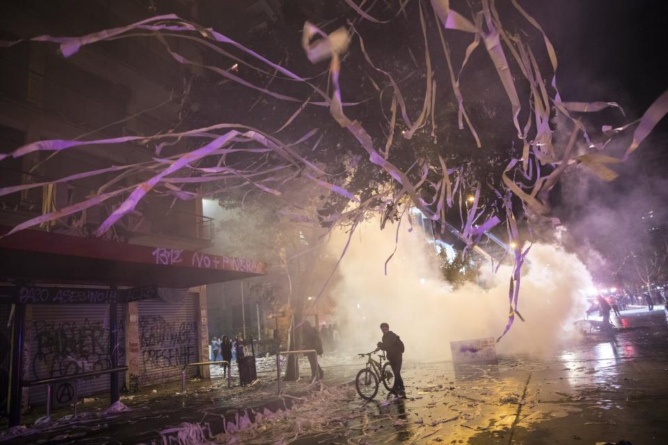 Paper hangs from the trees where a man walks amid the destruction caused by anti-government protests in Santiago, Chile, Monday, Oct. 28, 2019. Fresh protests and attacks on businesses erupted in Chile Monday despite President Sebastián Piñera's replacement of eight important Cabinet ministers with more centrist figures, and his attempts to assure the country that he had heard calls for greater equality and improved social services. (AP Photo/Rodrigo Abd)