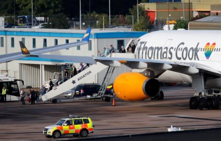 Passengers leave an airplane with the Thomas Cook livery at Manchester Airport