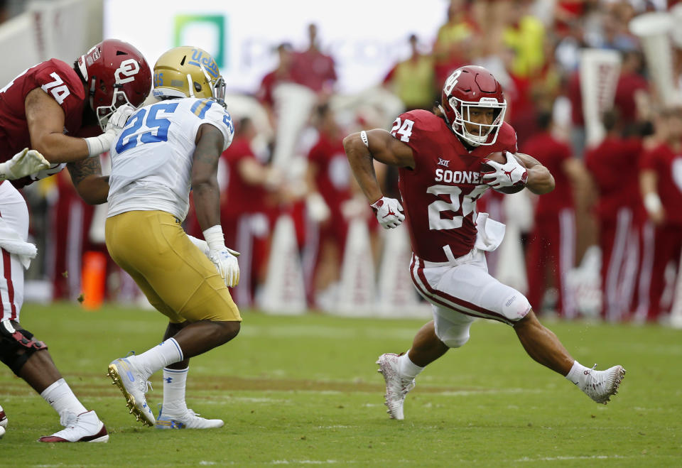 Oklahoma running back Rodney Anderson (24) runs around UCLA linebacker Tyree Thompson (25) in the first half of an NCAA college football game in Norman, Okla., Saturday, Sept. 8, 2018. (AP Photo/Sue Ogrocki)