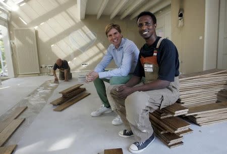 Tesfagebriel Abraha of Eritrea, 31, poses with his boss Daniel Kok (C) during his apprenticeship for a parquet recliner in Dortmund, Germany, August 31, 2015. REUTERS/Ina Fassbender/Files