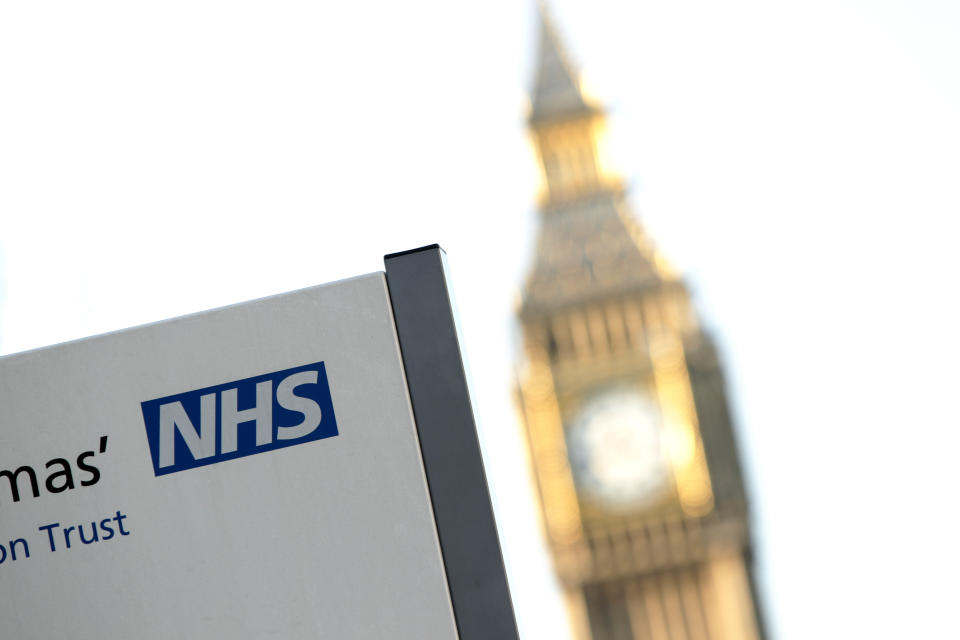 An NHS sign at St Thomas' Hospital, with Big Ben in the background, in Westminster, central London