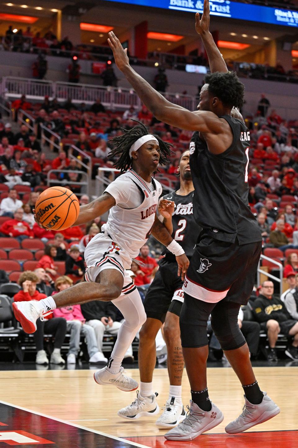 Louisville guard Ty-Laur Johnson looks to pass around New Mexico State forward Kaosi Ezeagu during the second half.