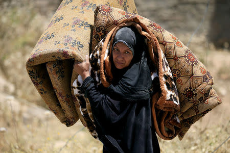 A displaced Iraqi woman who fled her home, carries a mattress in al-Zanjili neighbourhood, north of Old City district of Mosul, Iraq. REUTERS/Alaa Al-Marjani