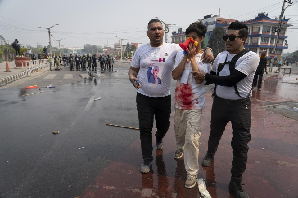 An injured supporter of Rastriya Prajatantra Party, or national democratic party is helped by his friends after clash with policemen as they take part in a protest demanding a restoration of Nepal's monarchy in Kathmandu, Nepal, Tuesday, April 9, 2024. Riot police used batons and tear gas to halt hundreds of supporters of Nepal's former king demanding the restoration of the monarchy and the nation's former status as a Hindu state. Weeks of street protests in 2006 forced then King Gyanendra to abandon his authoritarian rule and introduce democracy. (AP Photo/Niranjan Shrestha)