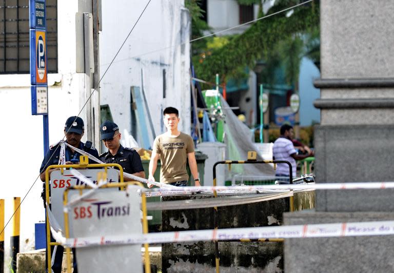 Two policemen check a back street next to a MRT train station where riots took place in Singapore's Little India district late on Dcember 8, 2013