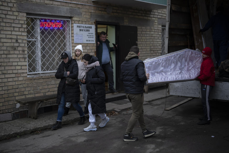 Anna Korostenska, left, and Anastasiia Okhrimenko, center, visit funeral homes in search of memorial candles to place at the cemetery in Bucha, Ukraine, Monday, Jan. 23, 2023. As the conflict that killed their loved ones still rages on, Anna, Anastasiia and her brother, Vadym wrestle with a question that all of war-torn Ukraine must grapple with: After loss, what comes next? (AP Photo/Daniel Cole)