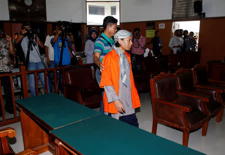 A plain clothes policeman guards Islamic cleric Aman Abdurrahman as he walks to the courtroom for his trial in Jakarta, Indonesia February 15, 2018. REUTERS/Beawiharta