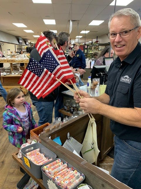 Lynn Miller, an employee at Yoder’s Country Market in Centreville, handed out flags for customers to wave when a group of military veterans arrived Saturday morning.