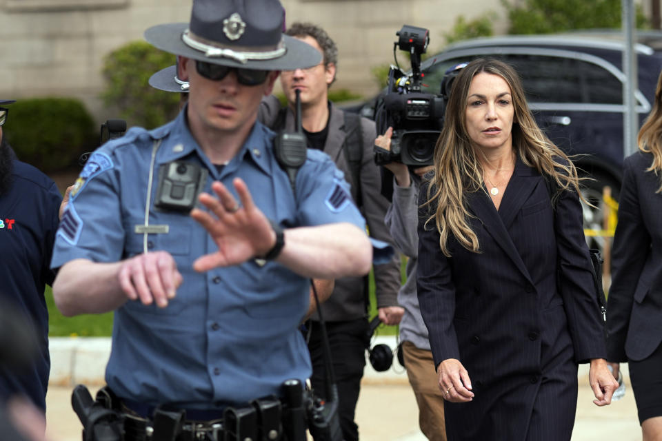 Karen Read, right, is flanked by Massachusetts State Police while leaving Norfolk Superior Court after the opening day of her trial, Monday, April 29, 2024, in Dedham, Mass. Read is charged with killing her Boston police officer boyfriend by intentionally driving her SUV into him. (AP Photo/Charles Krupa)