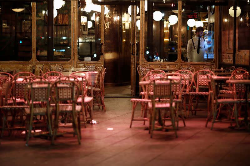 A waiter stands inside his empty restaurant and prepares the closure of the place, as France's Prime Minister announced to close most all non-indispensable locations from midnight on Saturday, in Paris