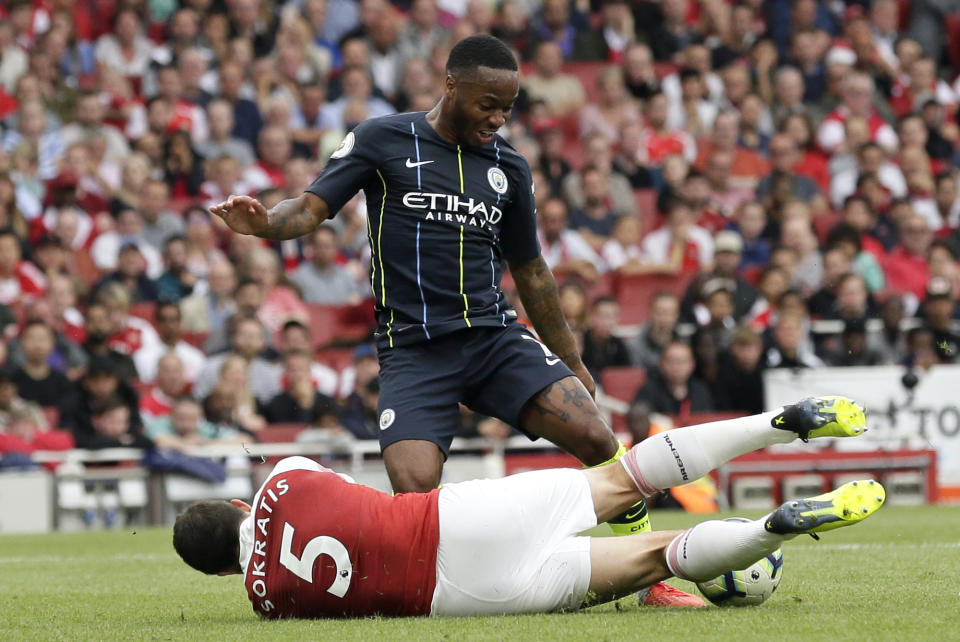 Arsenal's Sokratis Papastathopoulos falls down in front of Manchester City's Raheem Sterling during the English Premier League soccer match between Arsenal and Manchester City at the Emirates stadium in London, England, Sunday, Aug. 12, 2018. (AP Photo/Tim Ireland)