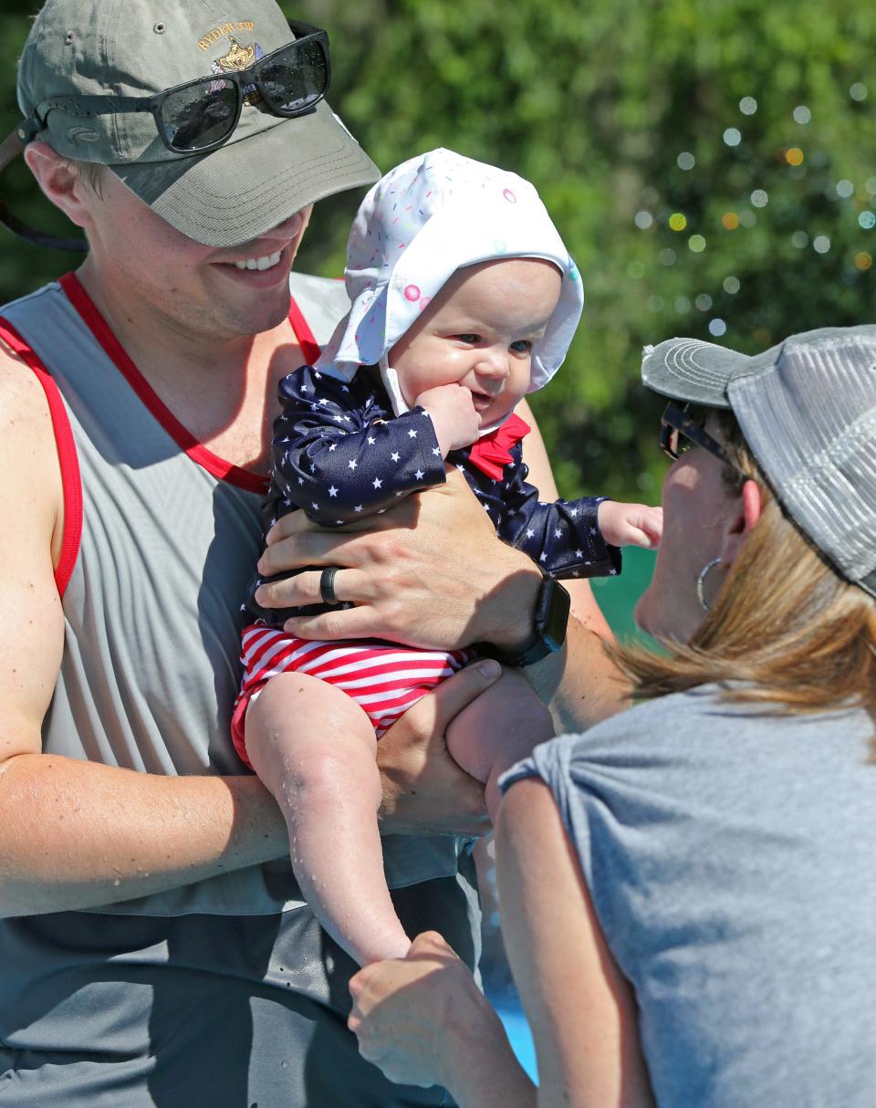 Joanna Burkett, center, is held by her father Trevor Burkett, left, while Janie Murphy, right, plays with her granddaughter after coming out of the splash pad at Veterans Park in Plain Township. Also along for the summer outing was Joanna's mother Ali Burkett.