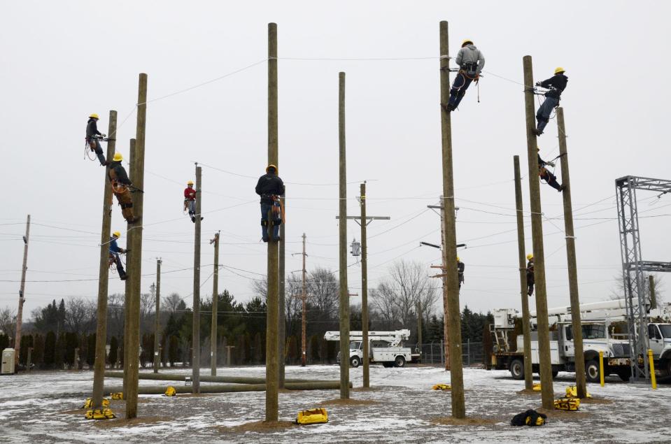 Students in a lineworker training program climb utility poles in December 2018 at the J.H. Farrington training area near Boyne Falls.
