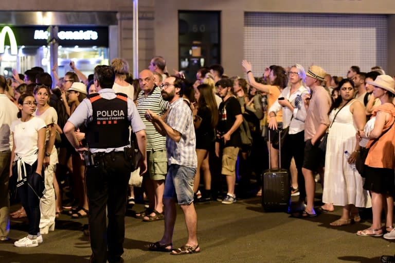 Tourists wait for the police to allow them to come back to their hotel on Las Ramblas boulevard after a van ploughed into the crowd, killing at least 13 people and injuring around 100 others on the Rambla in Barcelona, on August 18, 2017