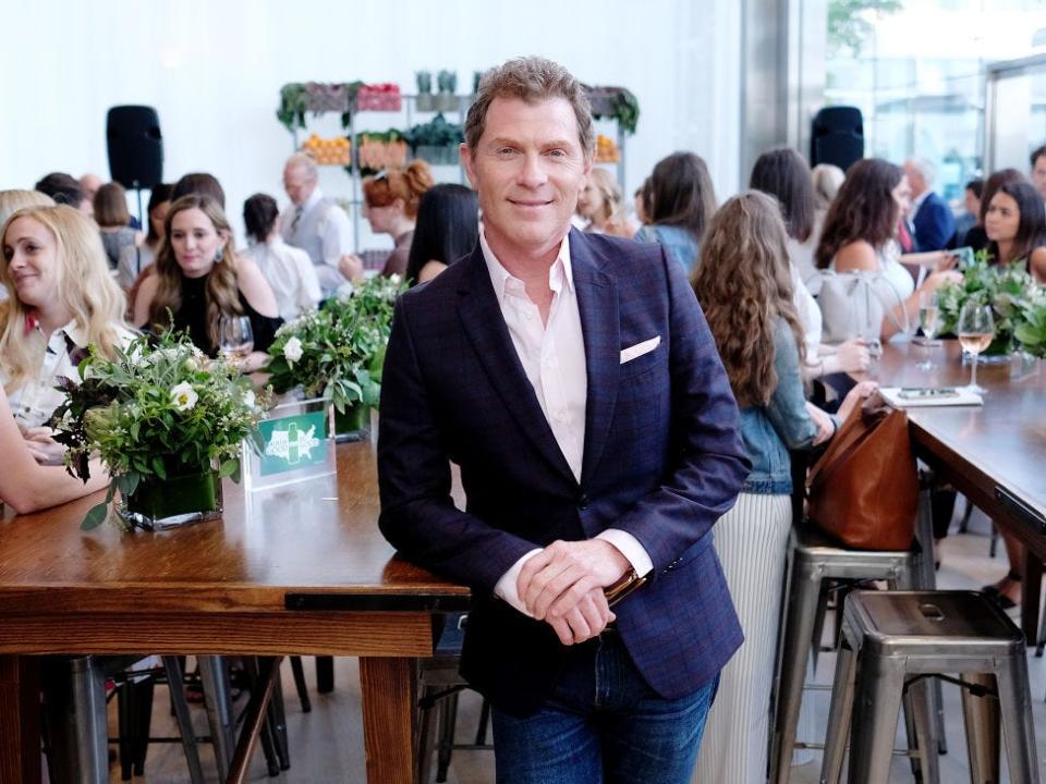 Bobby Flay leaning against a wooden table