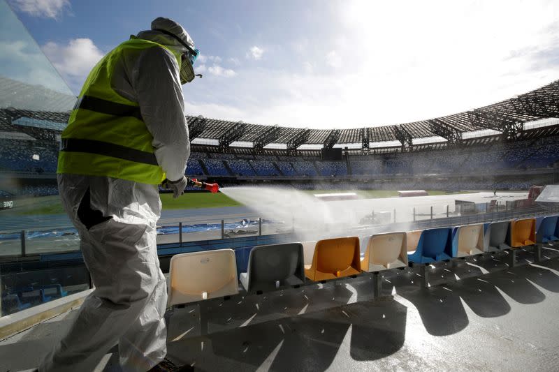 A cleaner wearing a protective suit sanitises seats at the San Paolo stadium ahead of the second leg of the Coppa Italia semi-final between Napoli and Inter Milan, which has since been postponed