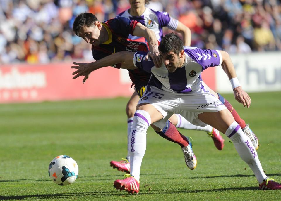 Barcelona's Lionel Messi from Argentina, left, and Valladolid's Stefan Mitrovic struggle for the ball during a Spanish La Liga soccer match at the Jose Zorrilla stadium in Valladolid, Spain, Saturday March 8, 2014. (AP Photo/Israel L. Murillo)