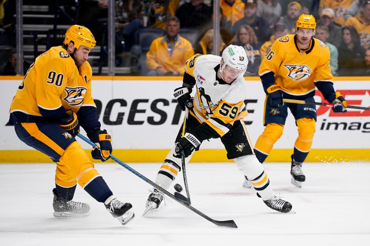 Pittsburgh Penguins left wing Jake Guentzel (59) shoots past Nashville Predators center Ryan O'Reilly (90) during the second period at Bridgestone Arena in Nashville, Tenn., Tuesday, Nov. 28, 2023.