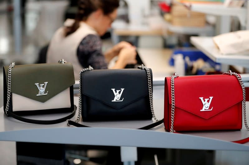 FILE PHOTO: Louis Vuitton handbags are displayed as an employee works in a Vuitton new high-end garment factory in Beaulieu-sur-Layon