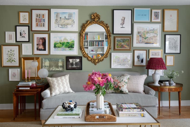 Gallery wall above gray couch with wood vintage end tables and vintage gold oval mirror