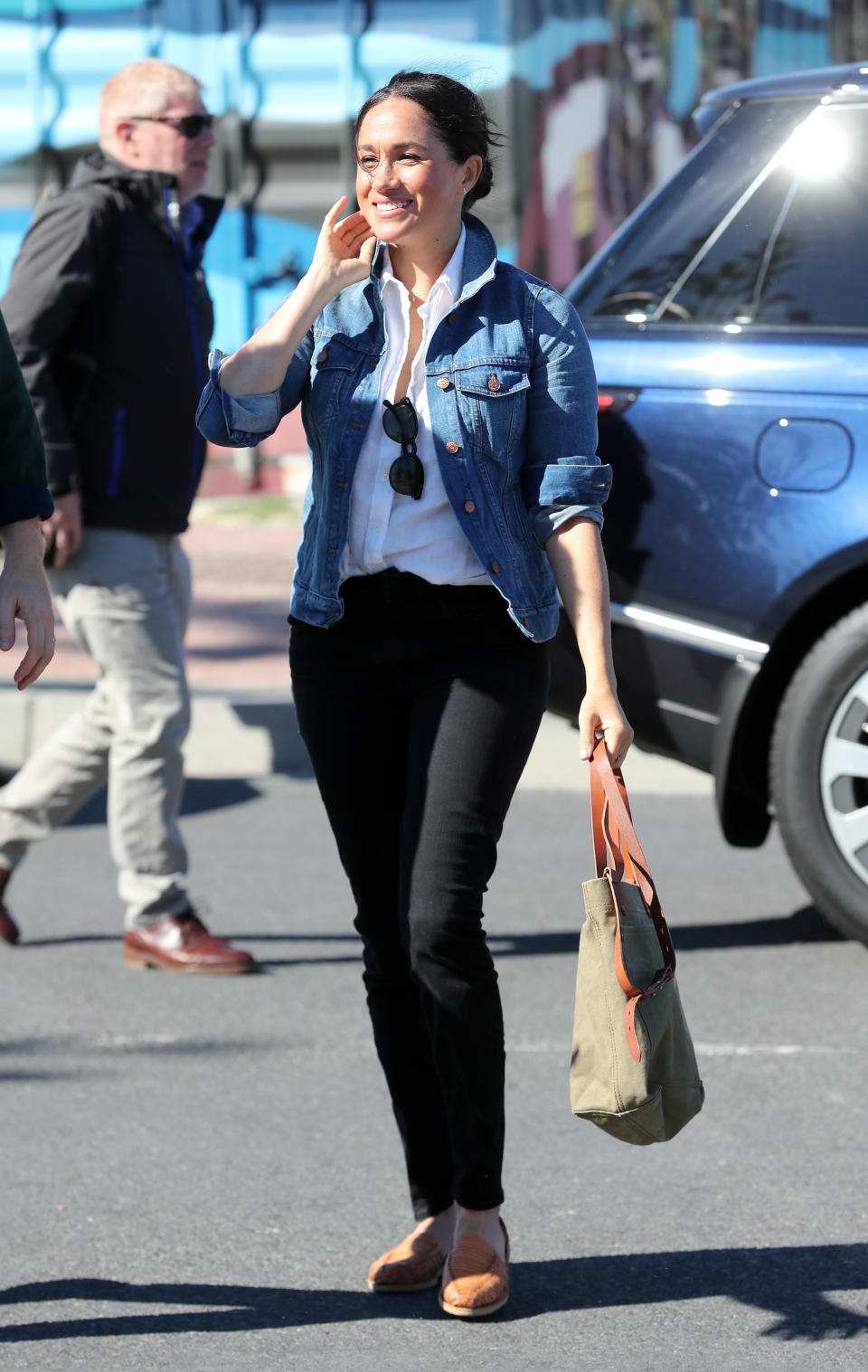 For a morning visit on day two of the tour, Meghan dressed down in a £111 denim jacket by Madewell, black jeans, a white shirt, old Brother Vellies shoes and an oversized tote bag. <em>[Photo: Getty]</em>