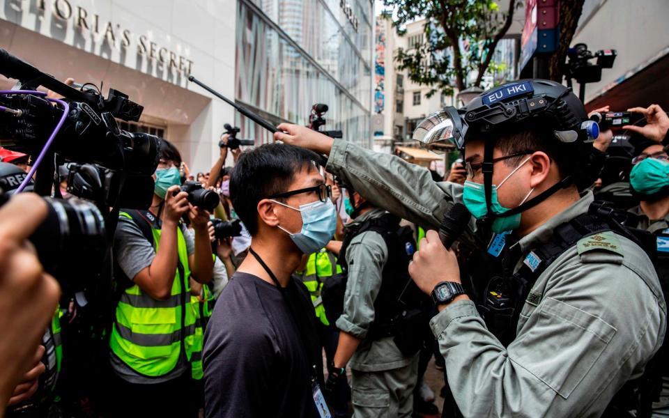 A protester argues with police during a demonstration over a bill banning insults to China's national anthem - ISAAC LAWRENCE /AFP