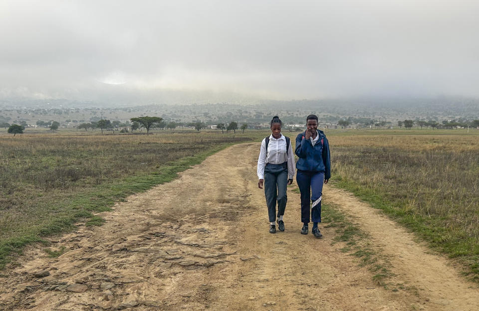 Luyanda Hlali, left, and her friend Mimi Dubazane embark on their routine 2 hour-long walk from the village of Stratford to their school in Dundee, South Africa, Thursday, Oct. 26, 2023. Thousands of children in South Africa's poorest and most remote rural communities still face a miles-long walk to school, nearly 30 years after the country ushered in democratic change. (AP Photo/ Mogomotsi Magome)