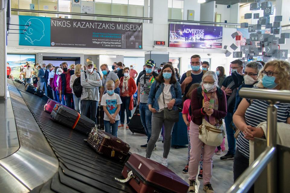 Passengers wait for their luggage at baggage claim conveyor belt.