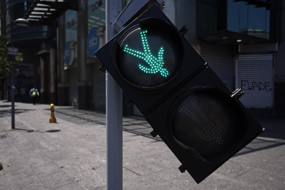 A pedestrian traffic light hangs crooked during riots as a state of emergency remains in effect in Santiago, Chile, Sunday, Oct. 20, 2019. Protests in the country have spilled over into a new day, even after President Sebastian Pinera cancelled the subway fare hike that prompted massive and violent demonstrations. (AP Photo/Luis Hidalgo)