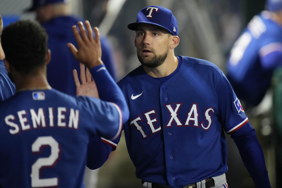 Texas Rangers starting pitcher Nathan Eovaldi, right, high-fives Marcus Semien in the dugout after the seventh inning of a baseball game against the Los Angeles Angels, Saturday, May 6, 2023, in Anaheim, Calif. (AP Photo/Jae C. Hong)