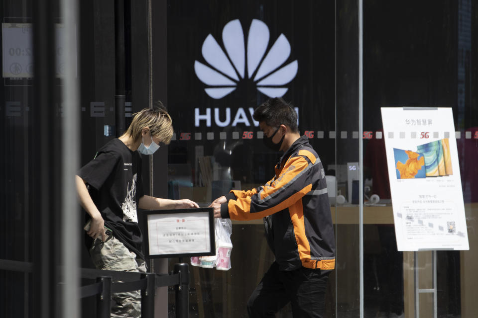 A delivery man hands over drinks near a Huawei retail store in Beijing on Monday, May 18, 2020. China's commerce ministry says it will take "all necessary measures" in response to new U.S. restrictions on Chinese tech giant Huawei's ability to use American technology, calling the measures an abuse of state power and a violation of market principles. (AP Photo/Ng Han Guan)