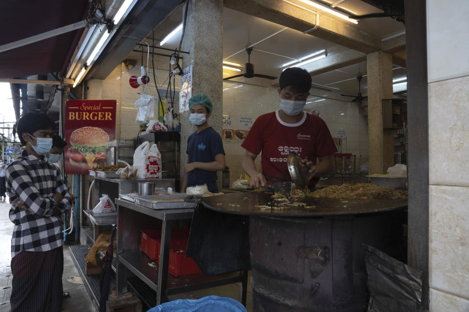 Customers wearing face masks wait for take-away meals ordered at a restaurant in Yangon, Myanmar,Monday, Sept. 21, 2020. Myanmar, faced with a rapidly rising number of coronavirus cases and deaths, has imposed the tightest restrictions so far to fight the spread of the disease in Yangon, the country's biggest city and main transportation hub. (AP Photo/Pyae Sone Win)