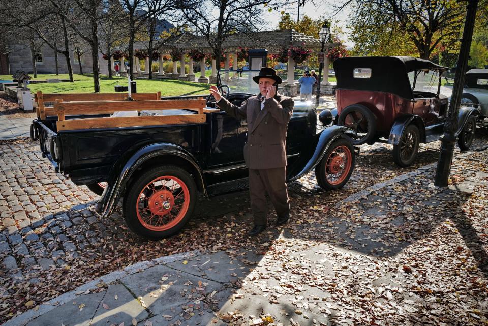 A cast member talks on the phone between filming, next to some vintage cars parked on the side of Acushnet Avenue as filming continues on a TV show set in the 1930s being filmed in downtown New Bedford.  The show titled, 'Invitation to a Bonfire,' will air on the AMC network.