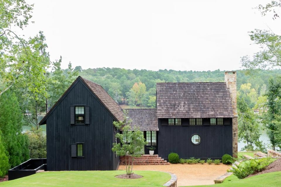 Black-painted salt box home with two adjoining buildings. 