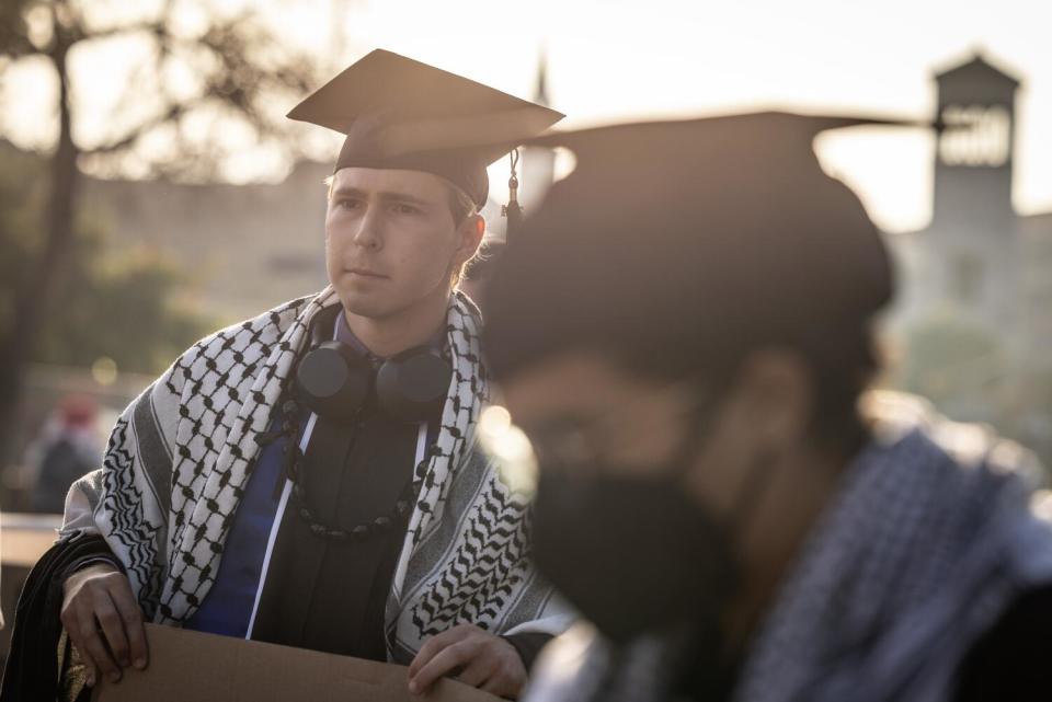 People wear caps and kaffiyeh shawls at a graduation ceremony.