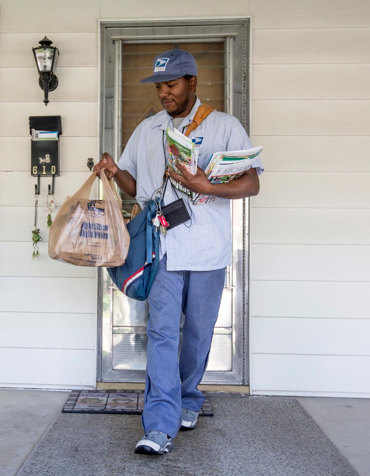 Letter carrier Sal Winters retrieves a bag of food donations from the front porch of a home in South Bend as part of the Stamp Out Hunger Food Drive in a recent year. ROBERT FRANKLIN, SOUTH BEND TRIBUNE