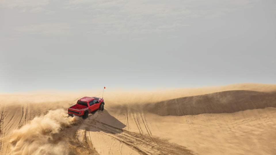 The 2023 Ford F-150 Raptor R driving up a sand dune.