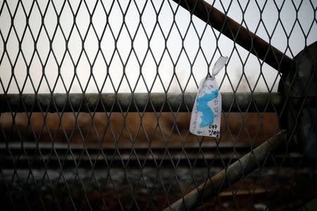 A unification flag hangs on a military fence near the demilitarized zone (DMZ) separating the two Koreas in Paju, South Korea January 15, 2018. The Korean character reads: "I want to walk freely beyond this military fence." REUTERS/Kim Hong-Ji