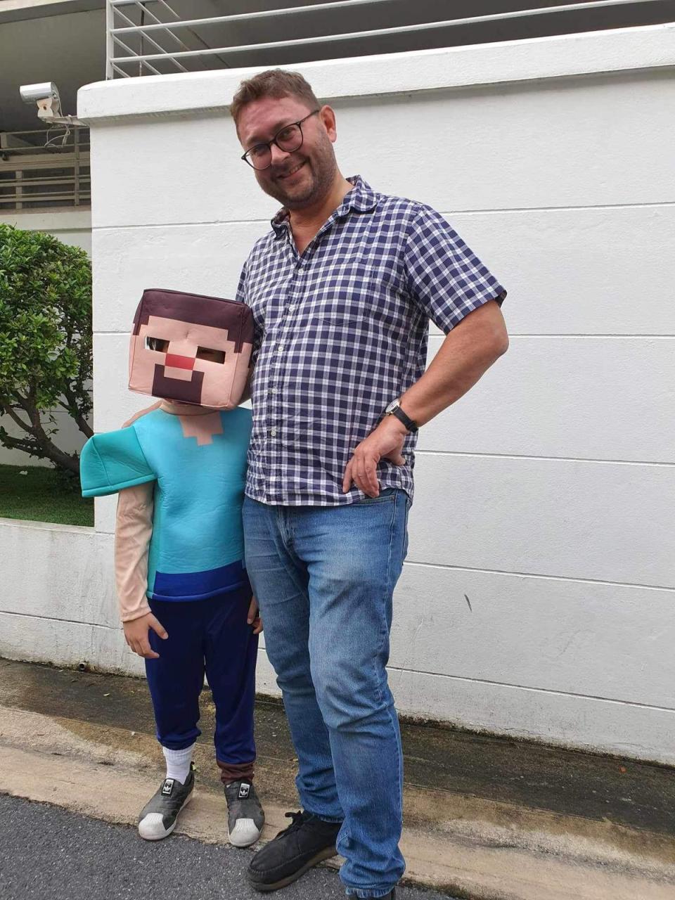 Father and son are standing together; son is wearing a Minecraft costume.