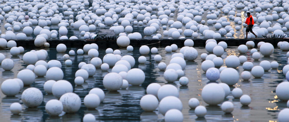 A worker walks on a floating walkway on Marina Bay amongst "wishing spheres" in Singapore