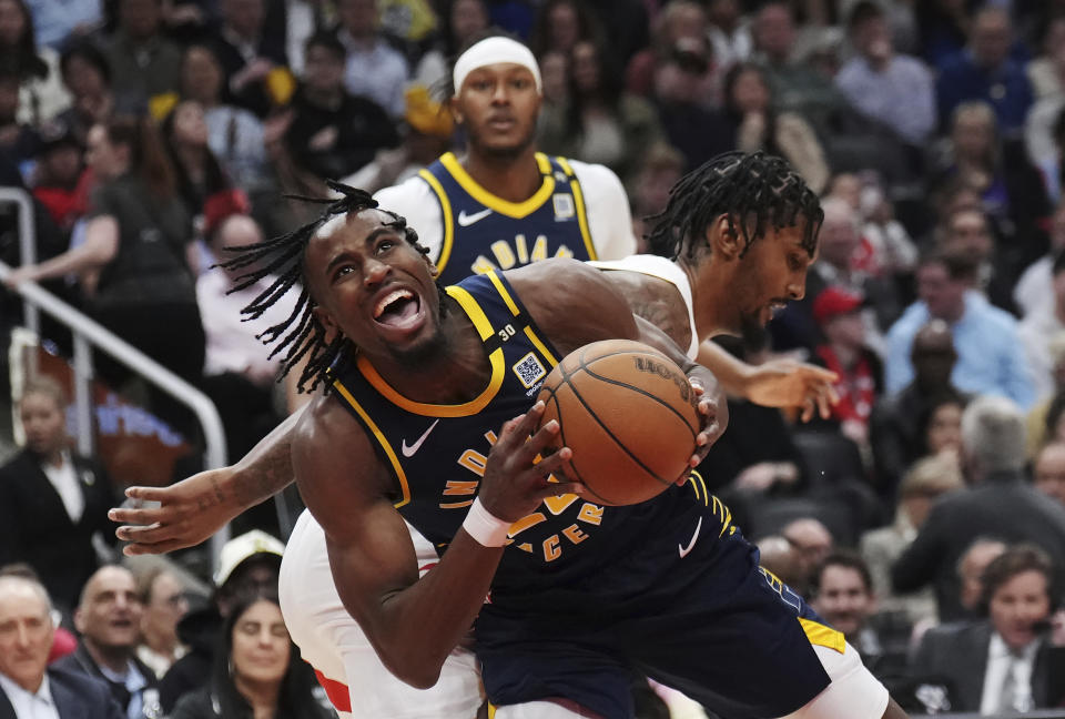 Indiana Pacers forward Aaron Nesmith, front, is tripped by Toronto Raptors center Malik Williams (35) during the first half of an NBA basketball game in Toronto on Tuesday, April 9, 2024. (Nathan Denette/The Canadian Press via AP)